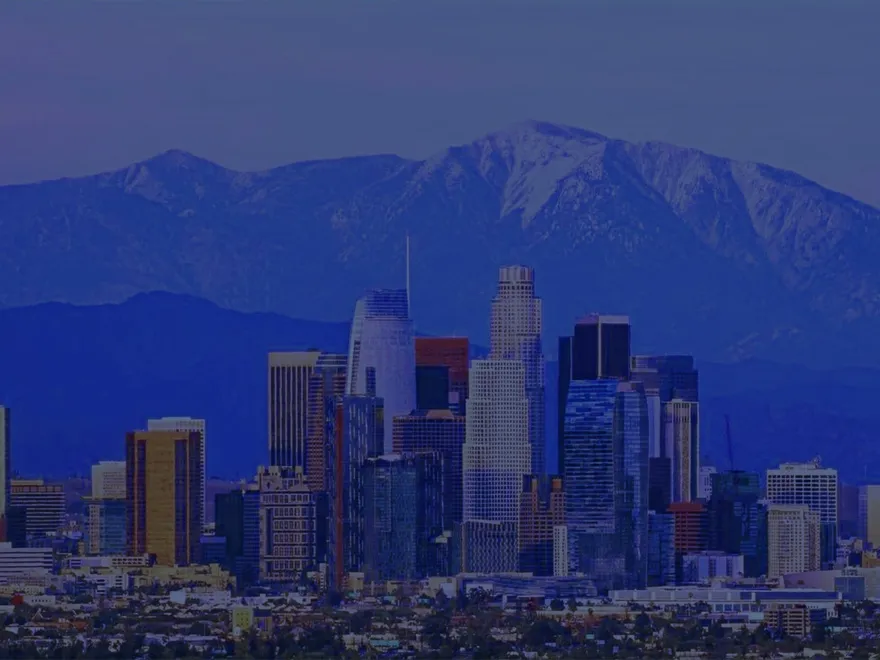 Los Angeles skyline at dusk with snow-capped mountains behind